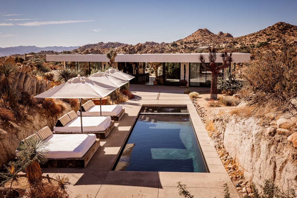 The Glasshouse pool and daybeds surrounded by boulders, one of the best Airbnbs in Joshua Tree, California