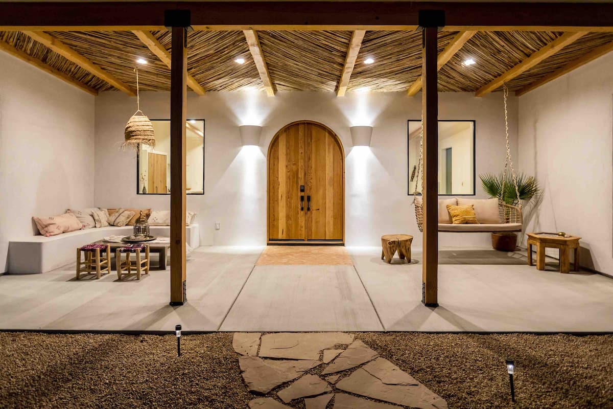 Desert Wild covered patio with arched wooden door, one of the best Airbnbs in Joshua Tree, California
