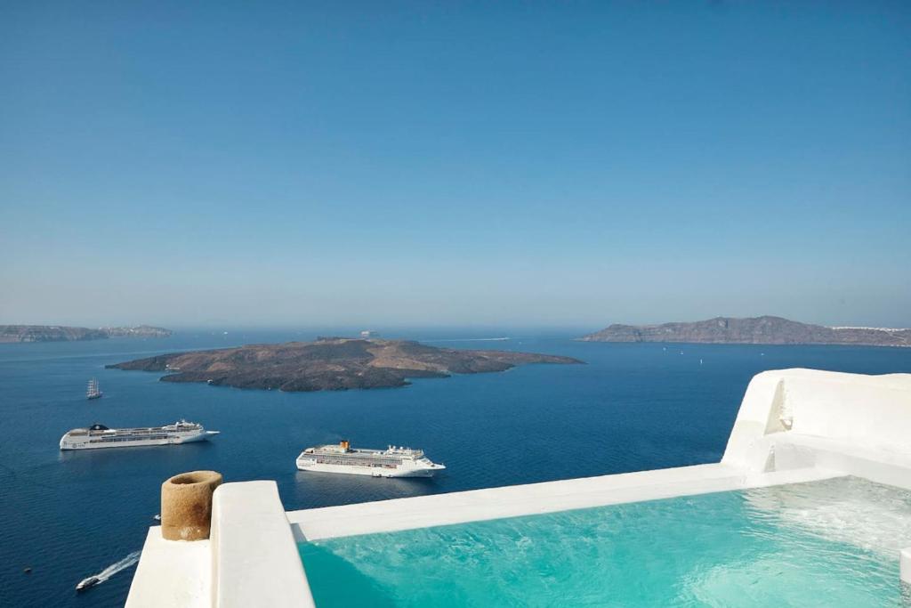 Swimming pool with boats on the water at Villa Murat, Fira Santorini